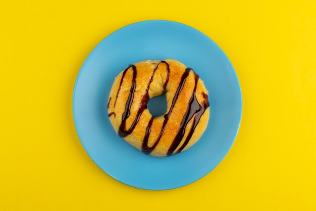 vista dall'alto ciambelle al cioccolato all'interno del piatto blu sul giallo