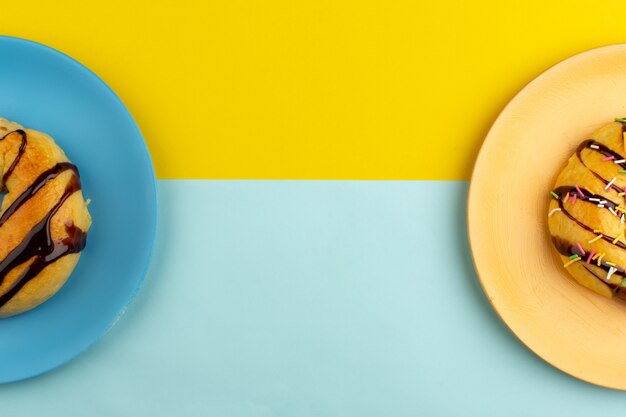 vista dall'alto ciambelle dolci deliziosi all'interno dei piatti sullo sfondo colorato