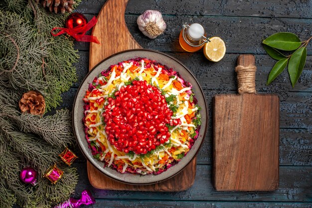 Vista dall'alto Cibo di Natale sulla tavola Piatto di Natale a bordo accanto alla tavola della cucina bottiglia di rami di olio con coni ciotola di spezie aglio limone