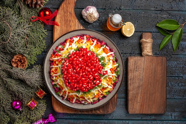 Vista dall'alto Cibo di Natale sulla tavola Piatto di Natale a bordo accanto alla tavola della cucina bottiglia di rami di olio con coni ciotola di spezie aglio limone