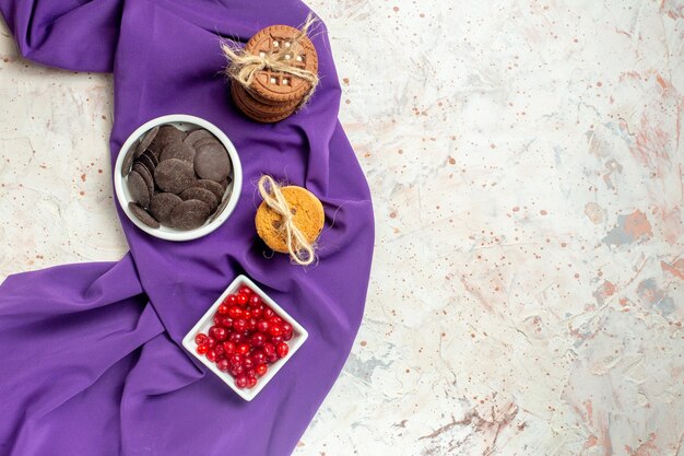 Vista dall'alto cioccolato e frutti di bosco in ciotole biscotti a scialle viola legati con una corda