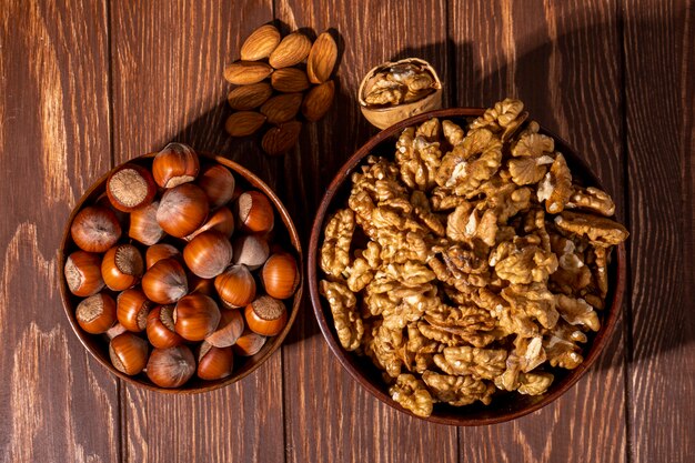 vista dall'alto ciotola con nocciole conchiglia con una ciotola di noci e mandorle sul tavolo