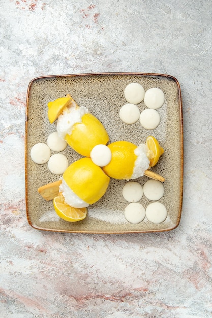 Vista dall'alto cocktail al limone con caramelle bianche sul succo di cocktail drink di frutta scrivania bianca