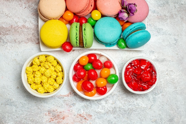Vista dall'alto colorati deliziosi macarons piccole torte con caramelle su uno spazio bianco