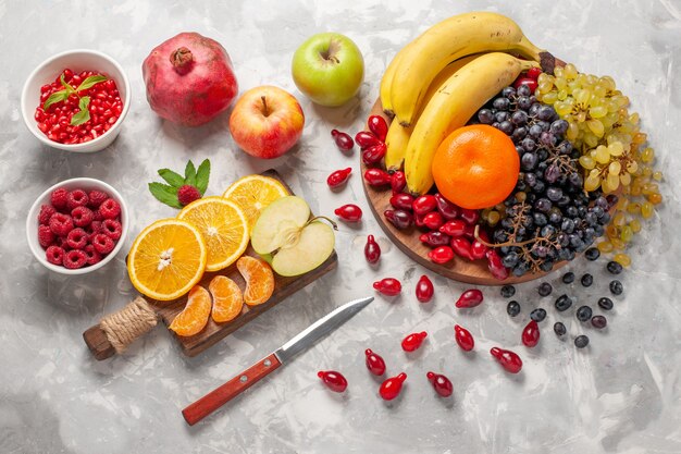 Vista dall'alto composizione di frutta fresca banane cornioli e uva sulla superficie bianco-chiaro frutta bacca freschezza vitamina