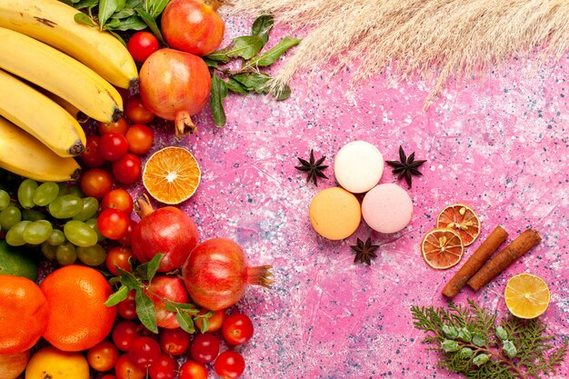 Vista dall'alto composizione di frutta fresca con macarons francesi su superficie rosa chiaro