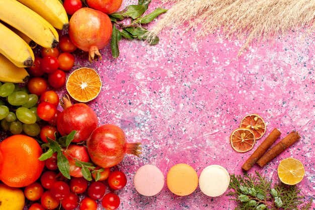 Vista dall'alto composizione di frutta fresca con macarons francesi su superficie rosa chiaro