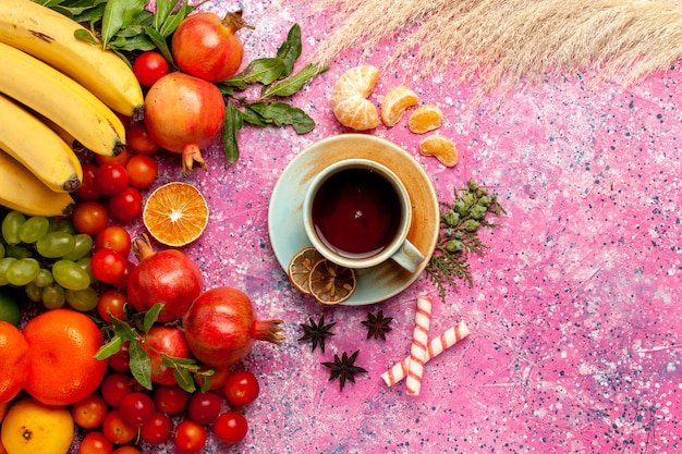Vista dall'alto composizione di frutta fresca con una tazza di tè sulla superficie rosa chiaro