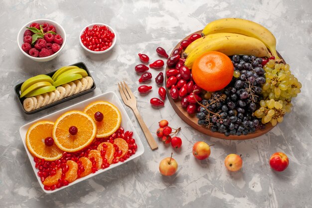 Vista dall'alto composizione di frutta fresca cornioli uva banane e arance sulla superficie bianca chiara frutta vitamina succo mellow vitamina