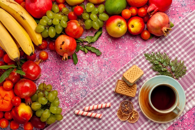 Vista dall'alto composizione di frutta fresca frutti colorati con una tazza di tè e cialde sulla superficie rosa