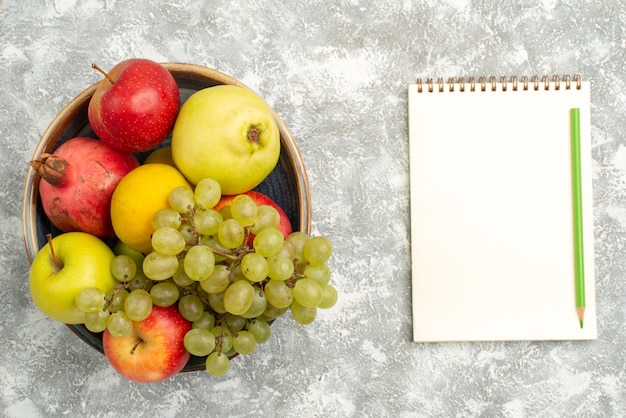 Vista dall'alto composizione di frutta fresca mele uva e altri frutti su sfondo bianco frutta fresca e pastosa colore maturo vitamina