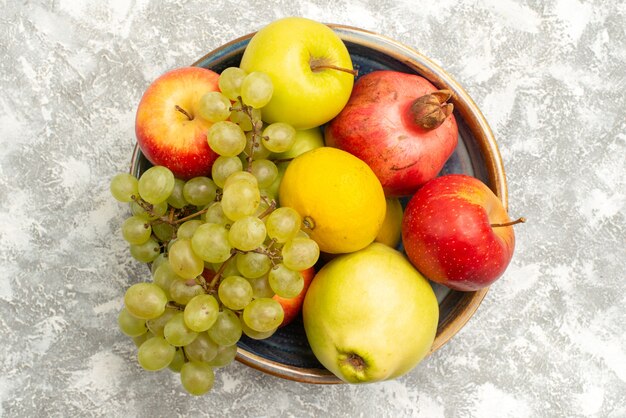 Vista dall'alto composizione di frutta fresca mele uva e altri frutti su superficie bianca fresca frutta pastosa colore maturo