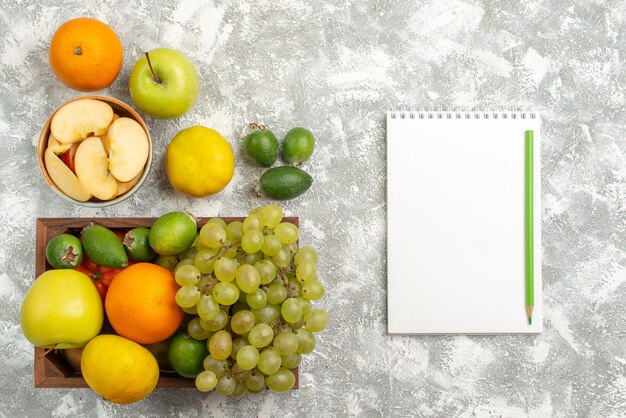 Vista dall'alto composizione di frutta fresca uva mele feijoa e altri frutti su sfondo bianco frutta fresca e pastosa colore maturo vitamina salute