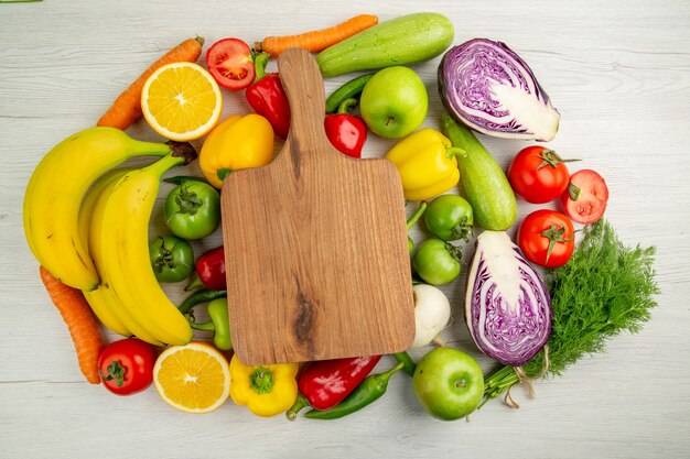 Vista dall'alto composizione vegetale pomodori cavolo peperoni con banane su sfondo bianco