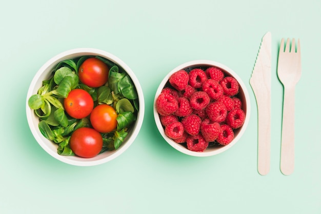 Vista dall'alto contenitori per alimenti con lamponi e insalata