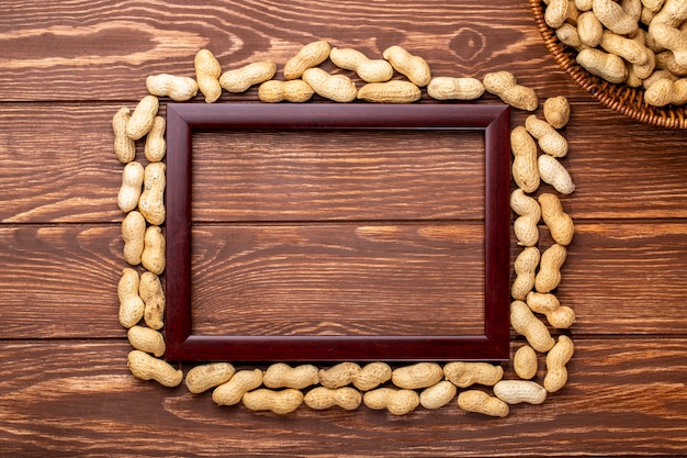 Vista dall'alto copia spazio cornice di legno intorno ai bordi arachidi in guscio su un tavolo di legno