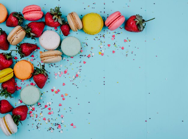 Vista dall'alto copia spazio macarons multicolori con fragole su sfondo blu