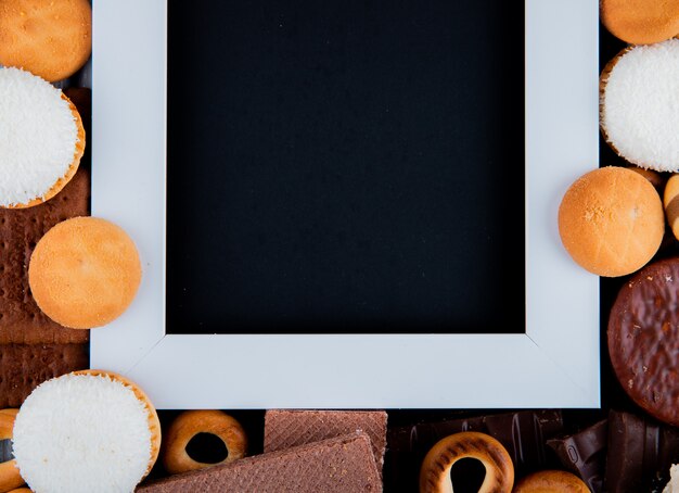 Vista dall'alto copia spazio mix di biscotti con marshmallow e una cornice bianca con uno sfondo nero