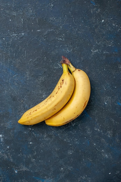 Vista dall'alto coppia di banane gialle di bacche sul tavolo scuro frutta
