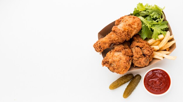 Vista dall'alto cosce di pollo fritte con ketchup e patatine fritte con copia-spazio