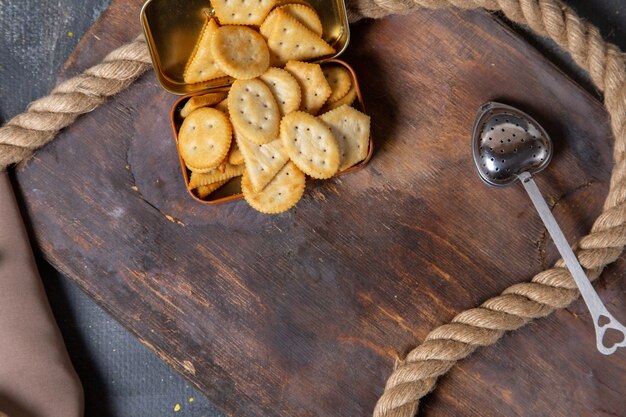 Vista dall'alto cracker patatine salate con corde sulla scrivania in legno sfondo grigio cracker snack croccante