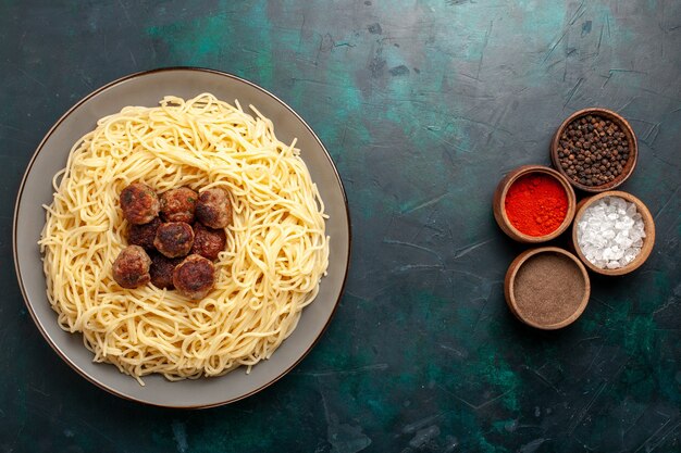Vista dall'alto cucinato pasta italiana con polpette di carne e condimenti sulla superficie blu scuro