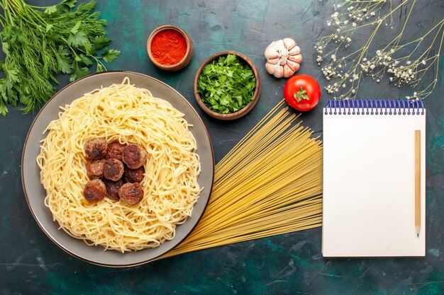 Vista dall'alto cucinato pasta italiana con polpette di carne e verdure sulla superficie blu scuro