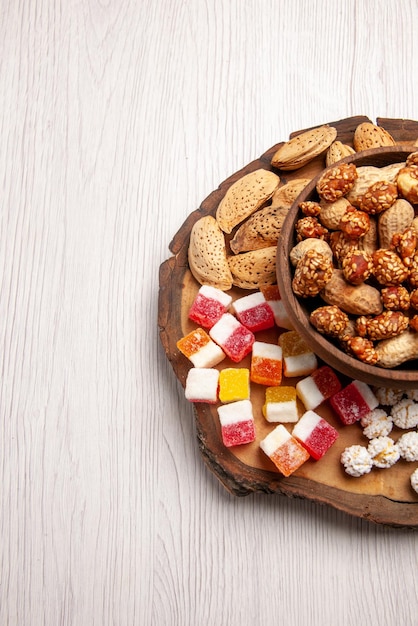 Vista dall'alto da lontano dadi sul tabellone arachidi dolci in una ciotola e diversi dolci sul tabellone della cucina sul tavolo