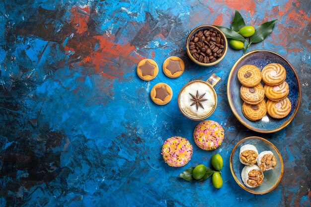 Vista dall'alto da lontano dolci biscotti diversi chicchi di caffè agrumi una tazza di caffè