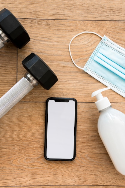 Vista dall'alto dei pesi con disinfettante per le mani e smartphone