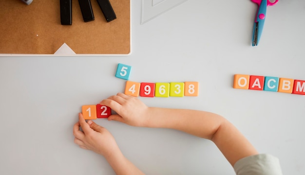 Vista dall'alto del bambino alla scrivania di apprendimento di numeri e lettere