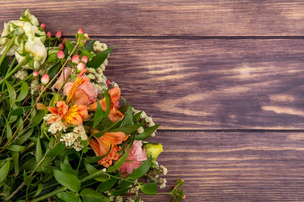 Vista dall'alto del bellissimo bouquet di fiori colorati con foglie su legno