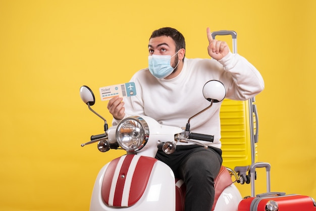 Vista dall'alto del concetto di viaggio con un giovane ragazzo curioso in maschera medica seduto sulla moto