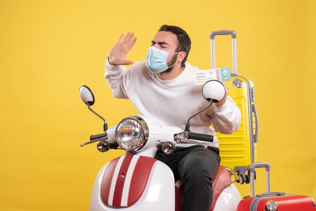 Vista dall'alto del concetto di viaggio con un giovane ragazzo nervoso in maschera medica seduto sulla moto