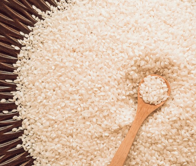 Vista dall&#39;alto del cucchiaio di legno su chicchi di riso bianco