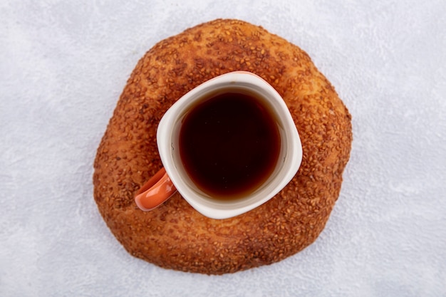 Vista dall'alto del delizioso bagel turco al sesamo con una tazza di tè su uno sfondo bianco