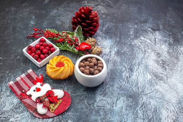 Vista dall'alto del delizioso biscotto accessorio per la decorazione del calzino di Babbo Natale e del cornell in una ciotola rami di abete sul lato destro sulla superficie scura