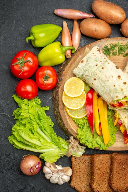 Vista dall'alto del delizioso sandwich di carne shaurma affettato con pane e verdure su nero