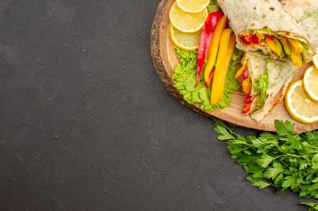 Vista dall'alto del delizioso sandwich di pollo a fette di shaurma con verdure al limone al buio