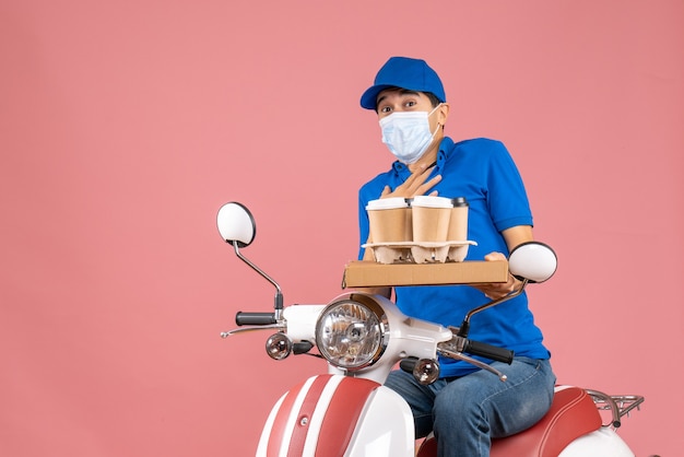 Vista dall'alto del fattorino maschio in maschera che indossa un cappello seduto su uno scooter che consegna gli ordini