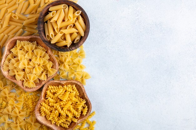 Vista dall'alto del mix di pasta cruda in ciotole su una superficie grigia