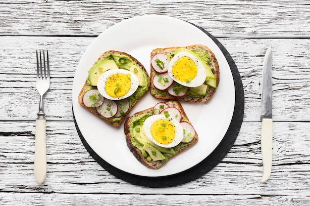 Vista dall'alto del piatto con uova e avocado panini e posate