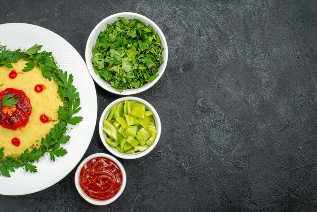 Vista dall'alto del piatto di purè di patate con salsa di pomodoro e verdure su grigio scuro