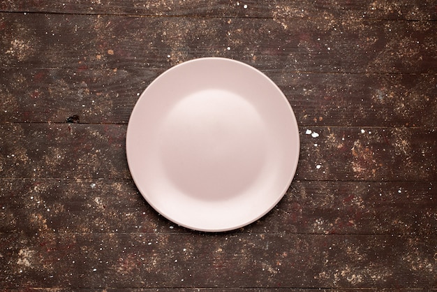 Vista dall'alto del piatto rosa vuoto isolato su piastra di legno rustico, legno marrone