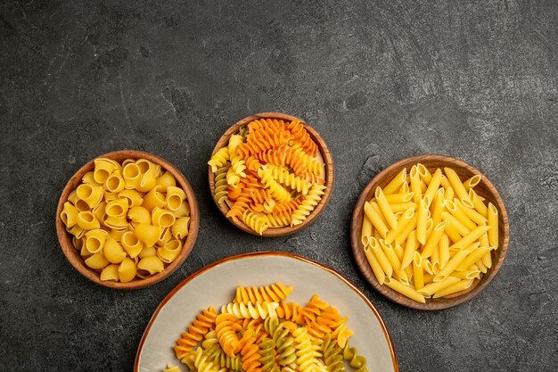 Vista dall'alto del prodotto crudo di diversa composizione di pasta all'interno dei piatti su grigio