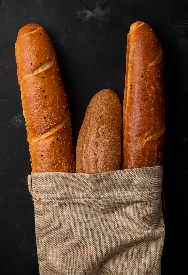 Foto gratuito vista dall'alto del sacco pieno di pane baguette su sfondo nero