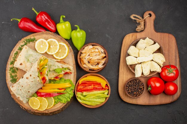 Vista dall'alto del sandwich di carne shaurma affettato con fette di limone e verdure su nero