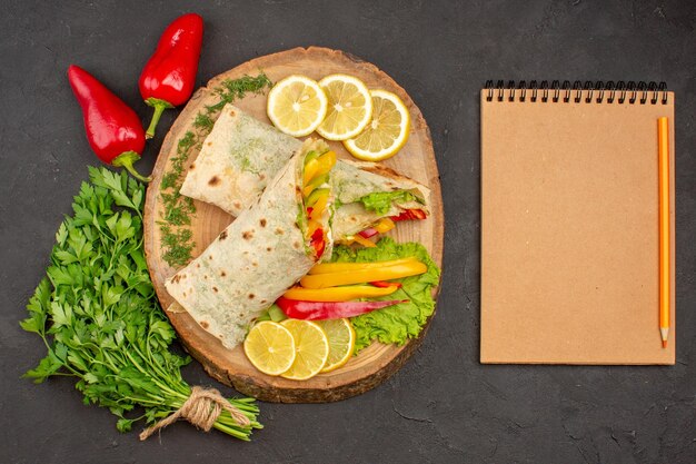 Vista dall'alto del sandwich di carne shaurma affettato con verdure lemonnd su nero