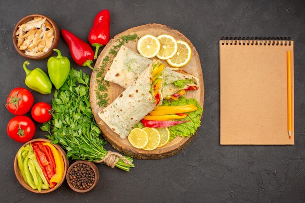 Vista dall'alto del sandwich di carne shaurma affettato con verdure lemonnd su nero