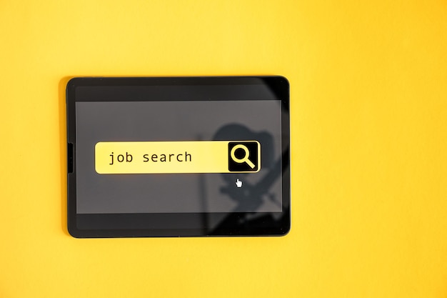 Vista dall'alto del tablet digitale con lavoro di ricerca sullo schermo su sfondo giallo